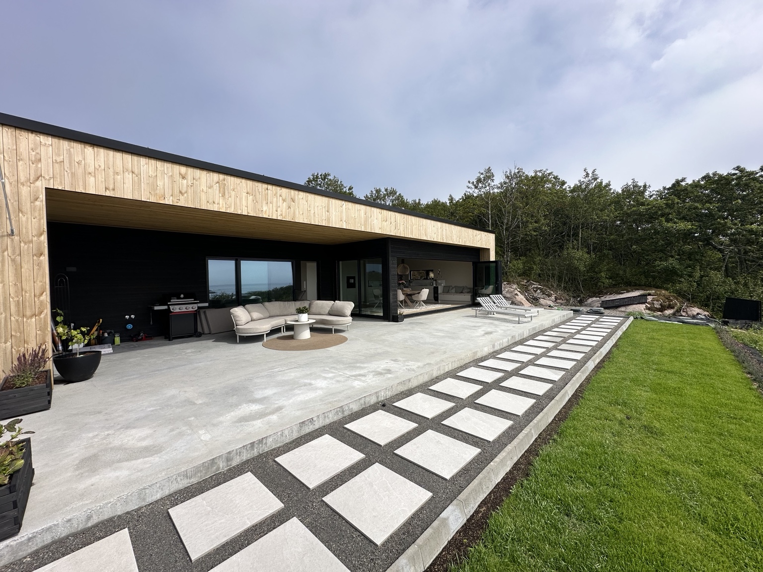 Moderne hus med overbygget terrasse og mørk trekledning