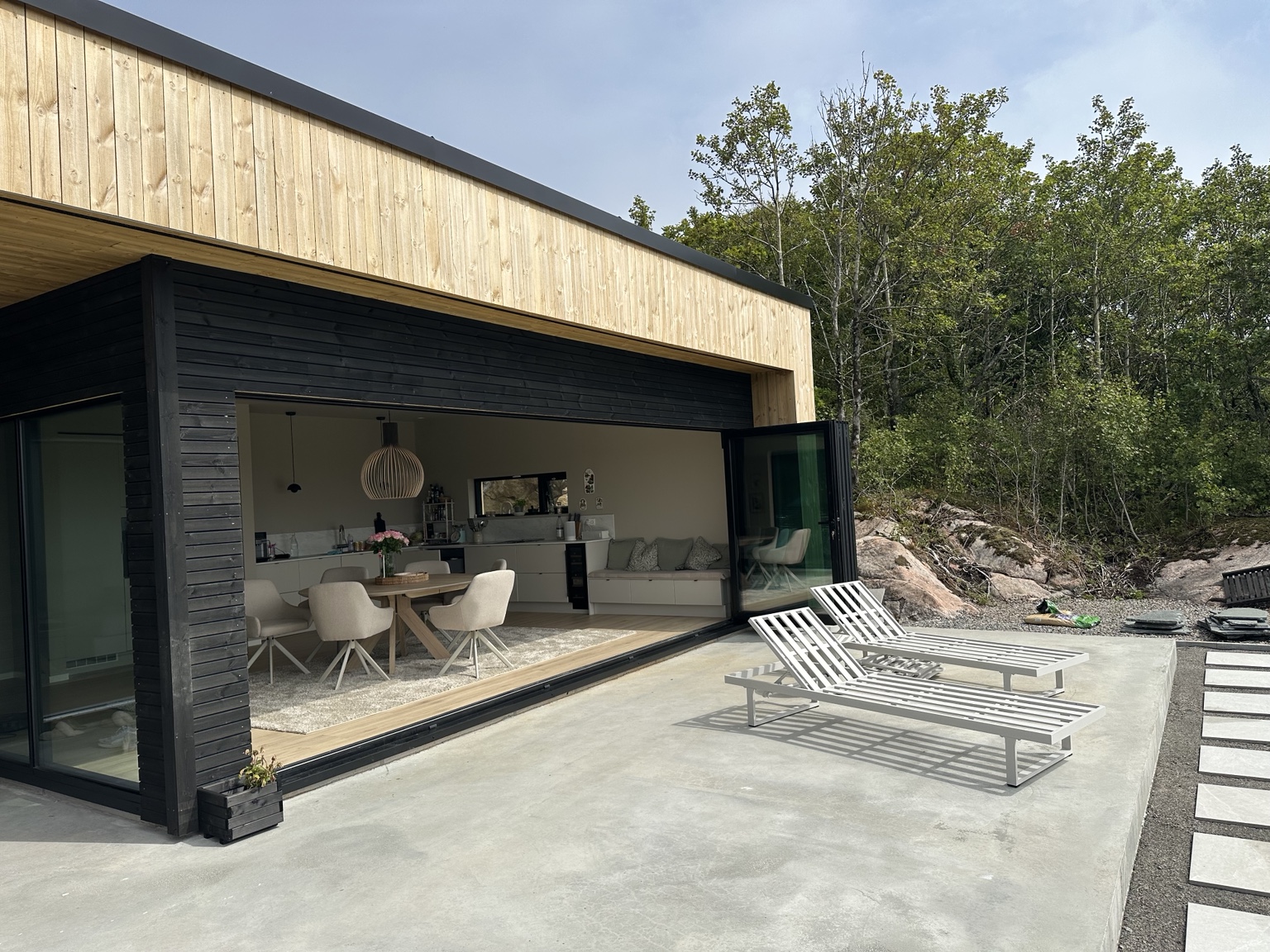 Terrasse med skyvedører, spiseplass og utsikt mot hagen