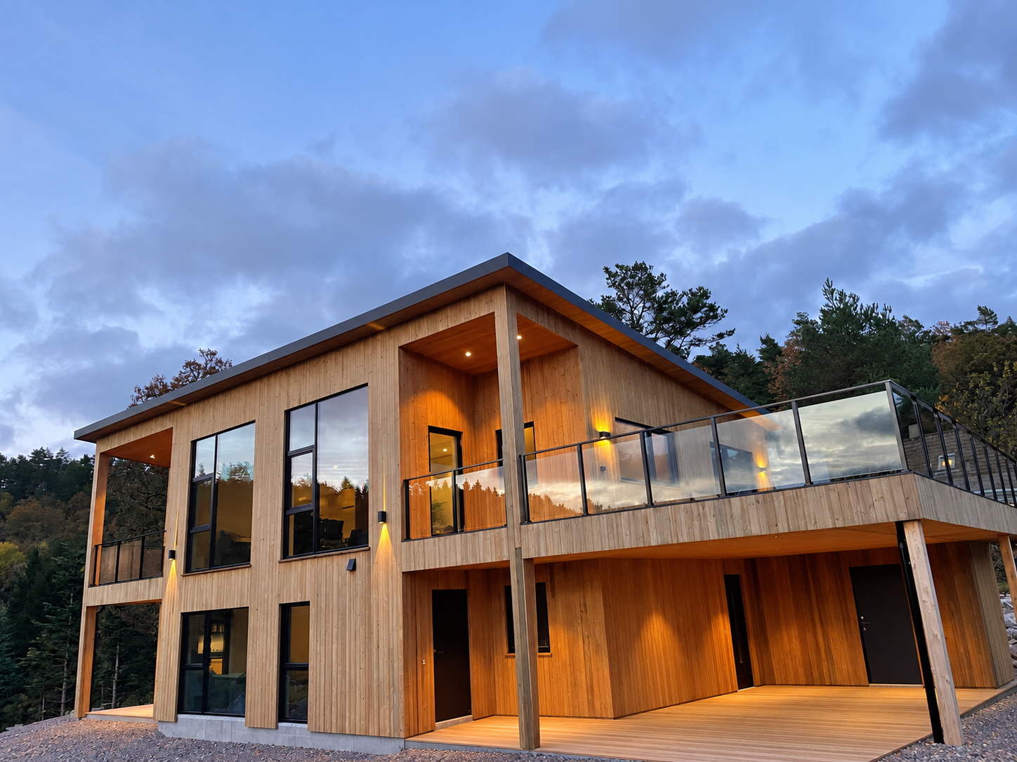 Moderne trehus med ryddet, overbygd terrasse og glassrekkverk