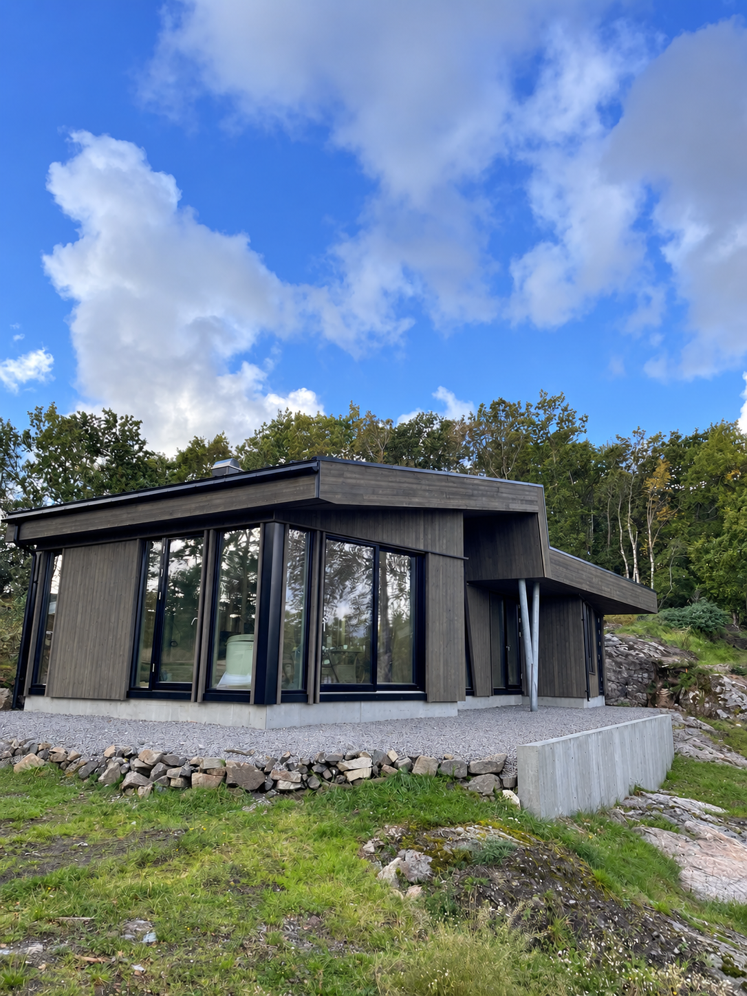 Moderne hus med mørk trekledning og store vindusflater