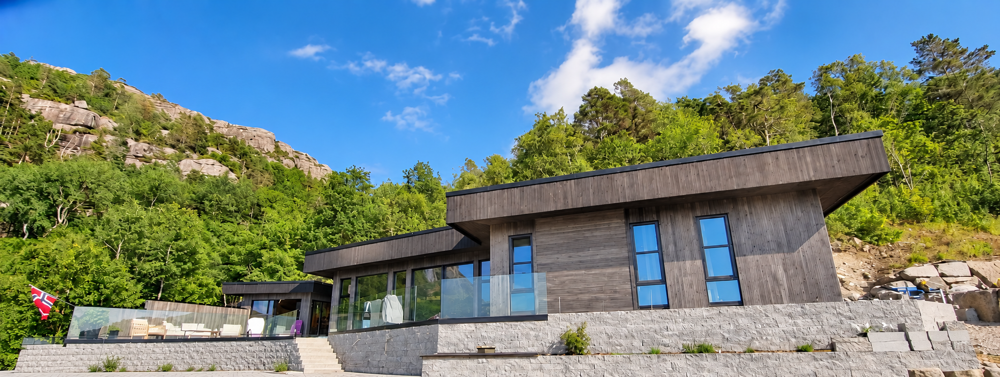 Moderne hus med mørk trekledning, terrasser og steinmurer